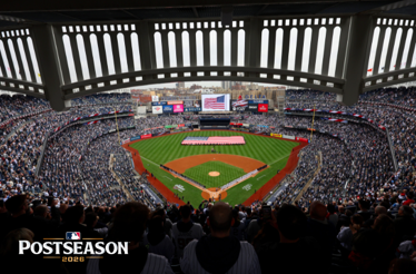 Yankee Stadium hosting a 2026 MLB Postseason game, with a large American flag displayed across the outfield during pre-game ceremonies.