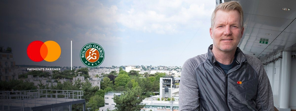 A photograph of Jim Courier with an urban scenery at the background. Roland-Garros in partnership with Mastercard logo is in the top left corner.