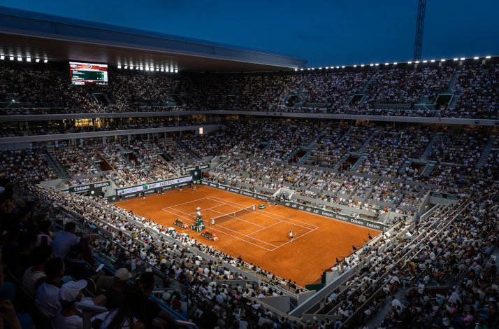A fan's wide view of a live tennis game in Roland-Garros stadium, filled with fans. 