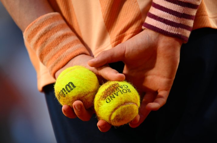 Wilson Roland Garros tennis balls in hands behind back.