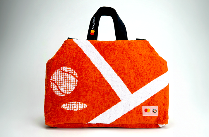 Orange terry cloth tote bag made from upcycled Roland-Garros towels featuring white court line design, tennis ball pattern, black handles with 