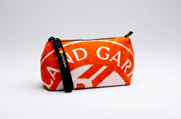 Orange Roland-Garros toiletry bag with a black strap.