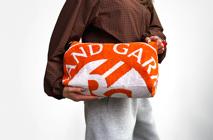Person carrying a Roland-Garros toiletry bag with a strap.