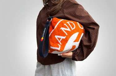 Person holding an orange Roland-Garros toiletry bag.