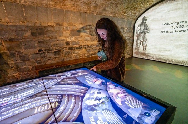 A visitor interacting with a large digital touch-screen display inside EPIC The Irish Emigration Museum in Dublin.