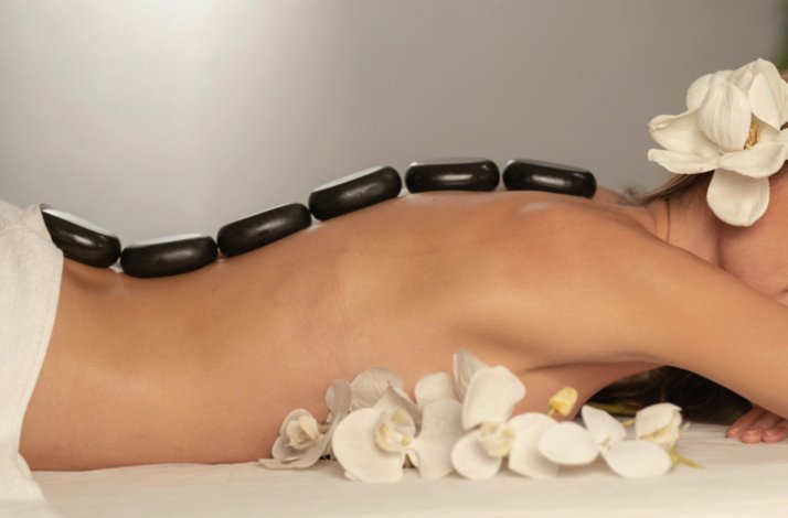 Hot stone massage setup with orchids for ultimate relaxation.