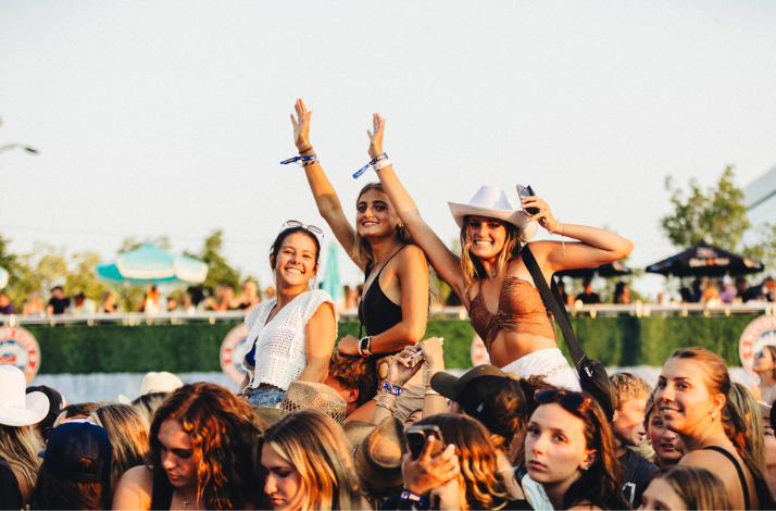 Excited festival-goers cheering and raising their hands in the crowd at Lone Star Smokeout.