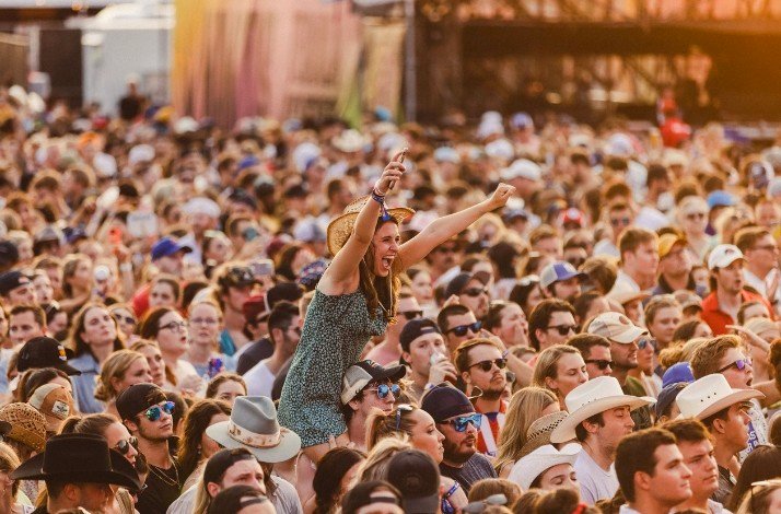 A girl sitting on a man's shoulders enjoys country music concerts.