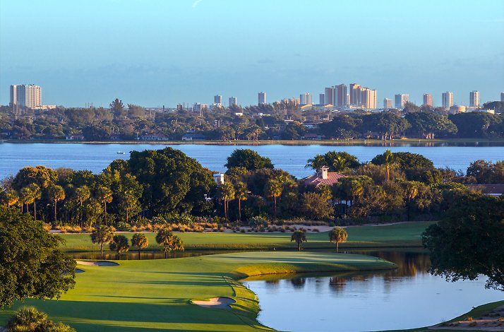 Golf course with water views and city skyline.