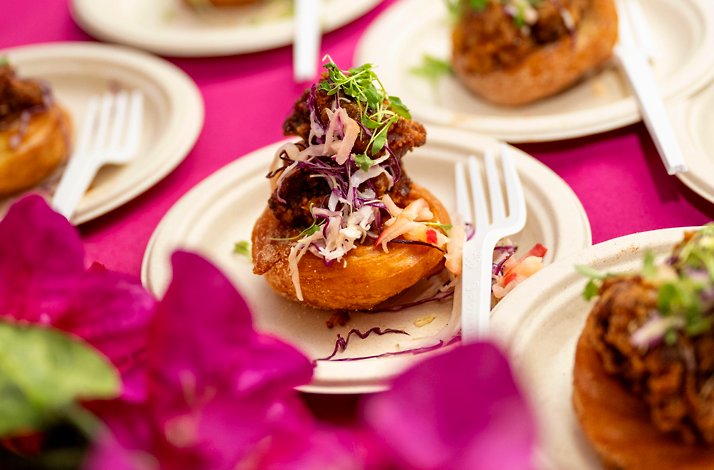Close-up of a gourmet appetizer with fried chicken, slaw, and microgreens on a small plate.