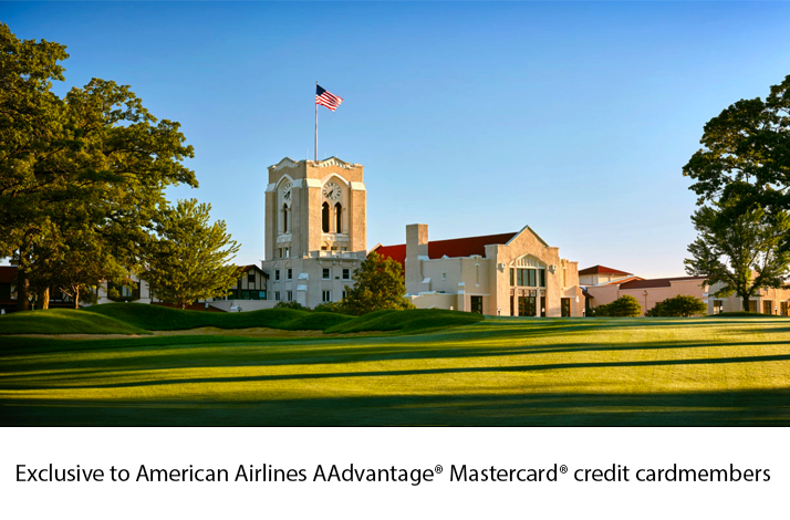 Olympia Fields clubhouse with tower and American flag overlooking a sunlit fairway.