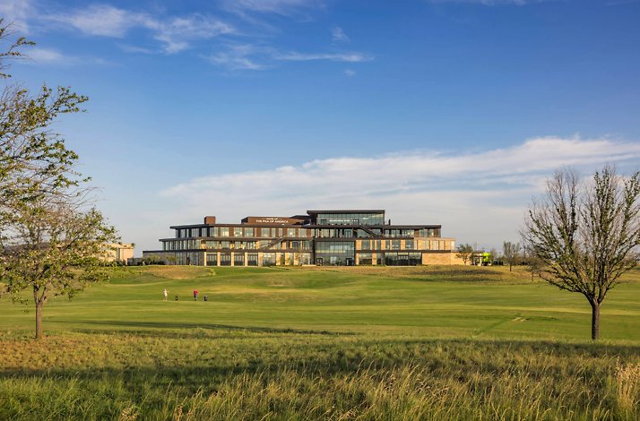 Modern PGA of America clubhouse with glass facade, set on open green fairways.