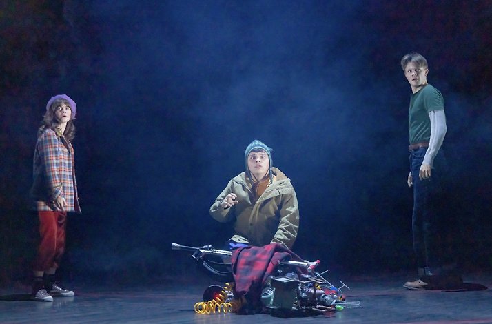 Scene from the Broadway's Stranger Things: The First Shadow performance: 2 boys and a girl look at something in the dark with a terrified look on their faces.