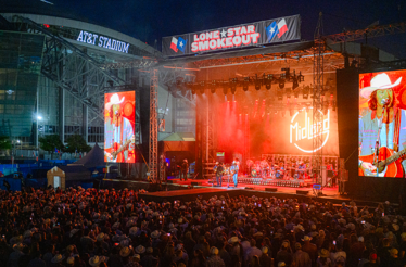Midland performing live on stage at the Lone Star Smokeout festival outside AT&T Stadium at night.