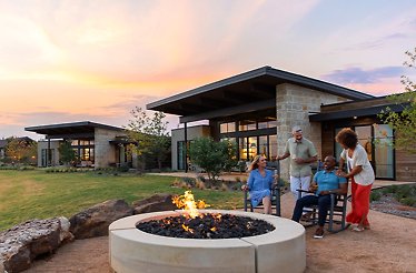 People relaxing next to a fire pit at the Omni Ranch House.
