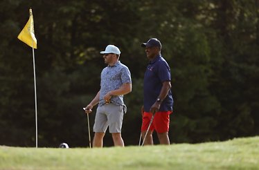 Two people playing golf at Drive Fore Kids Tournament.
