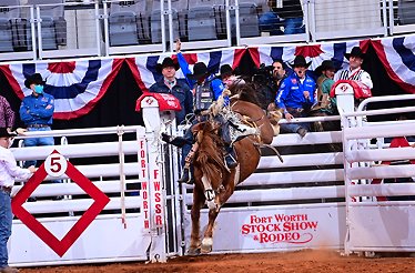 A man skillfully rides a horse in a rodeo arena, showcasing his talent amidst a lively crowd.