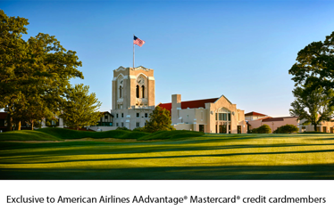 Olympia Fields clubhouse with tower and American flag overlooking a sunlit fairway.