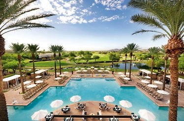 Aerial view of Fairmont Scottsdale Princess' resort pool surrounded by palm trees, lounge chairs, and a lush golf course beyond.