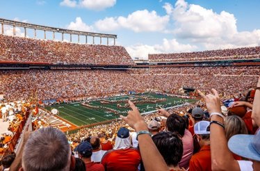 People on the tribunes watching the game at Darrell K Royal-Texas Memorial Stadium.