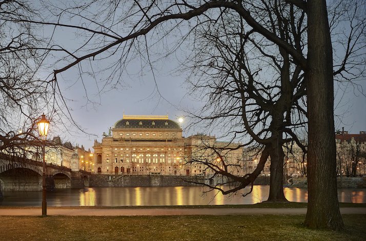 View at the embankment of Vltava river with a building of the Prague National Theatre in the evening street lights.