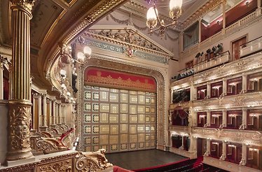 Interior of Prague National Theatre with ornate gold curtain.