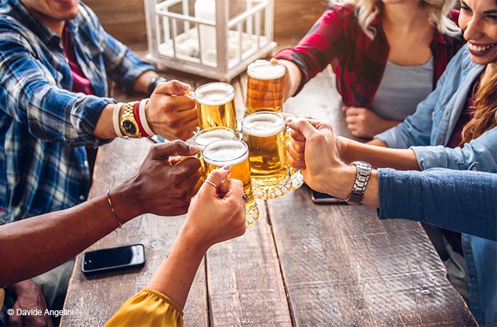 A group of people clinking glasses of beer. © Davide Angelini