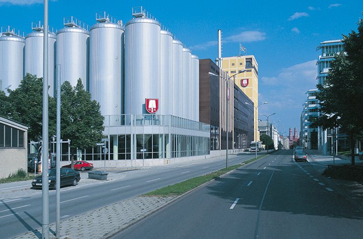 Spatenbrauerei brewery exterior featuring towering silver fermentation tanks and Spaten logo on a sunny Munich street.