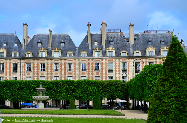 The architectural grandeur of Place des Vosges in the historic Le Marais district, set against a backdrop of green foliage. Photo by Amin Zabardast on Unsplash.