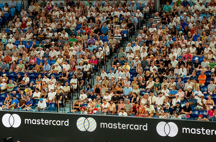 Spectators fill stadium seating above courtside Mastercard advertising boards.