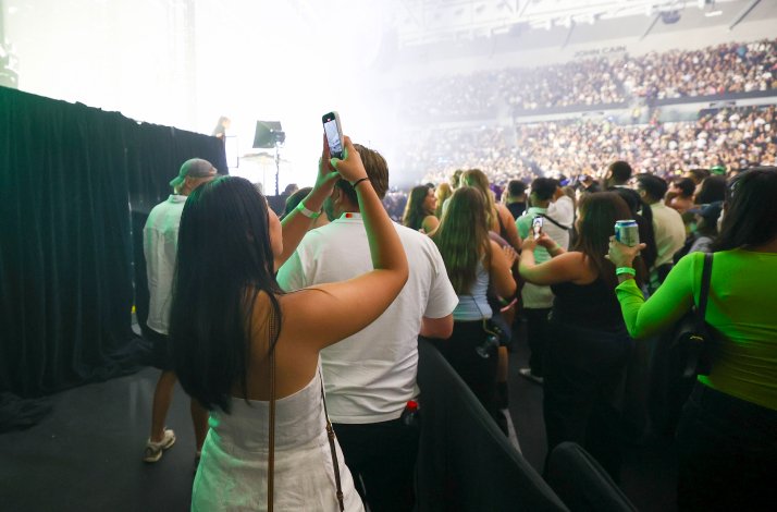 A girl taking a picture at Australia Arena, fully crowded.