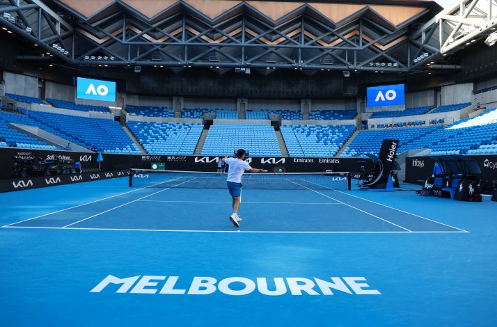 Two people playing tennis in the field at an empty Rod Laver Arena, Melbourne.