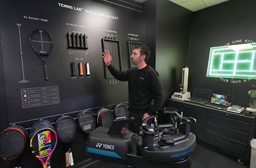 A person demonstrating tennis bats and other items displayed for AO Championships.