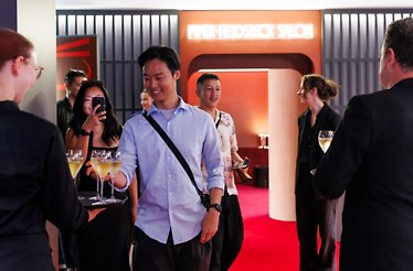 A man takes a glass of champagne from a waiter’s tray at Rod Laver Arena in Melbourne.