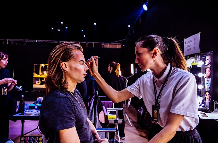 A makeup assistant applying acrobats' makeup to one of the visitors to Cirque du Soleil's International Headquarters.