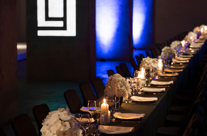 The table is elegantly decorated with white floral centerpieces and numerous lit candles at Berlinale private dinner.