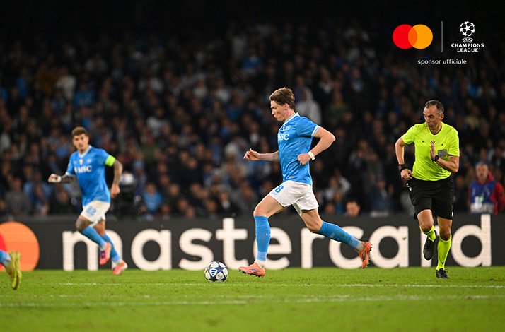 SSC Napoli player dribbling forward with the ball at Stadio Diego Armando Maradona during Napoli v Eintracht Frankfurt. Mastercard and UEFA Champions League logos at the top right corner.