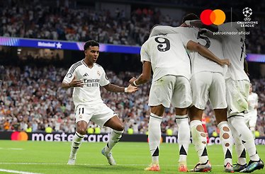 Football players at UEFA Champions League game with Mastercard logo on the promotional banner next to the field.