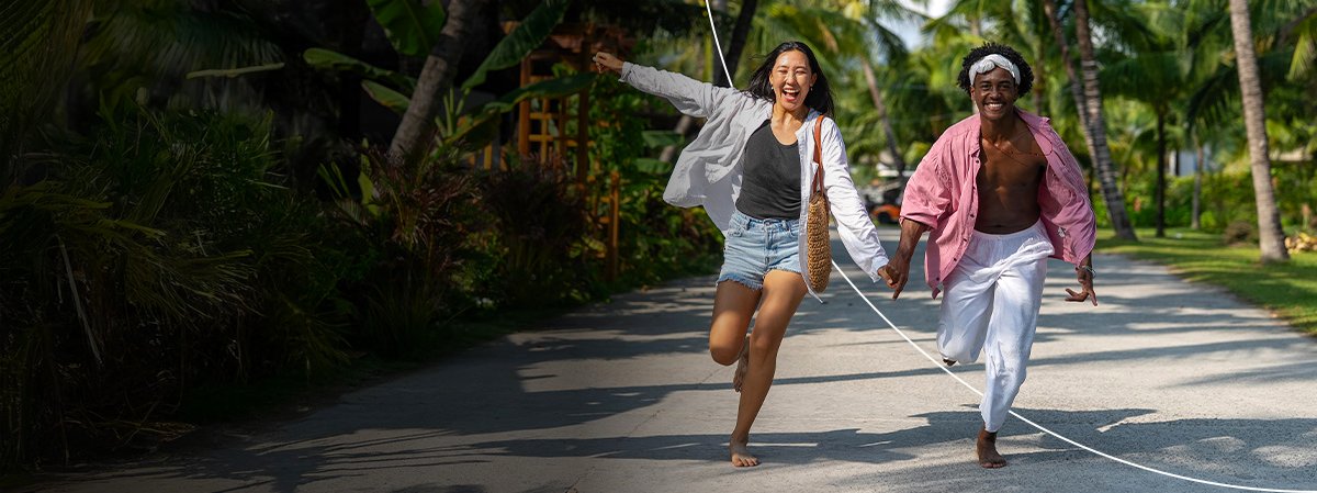 Two people running happily along a tropical alley.