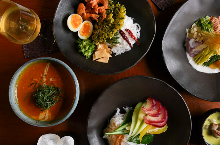 Food shot showcases a table setting with Thailand's diverse regional cuisines, complemented by a wine glass. 