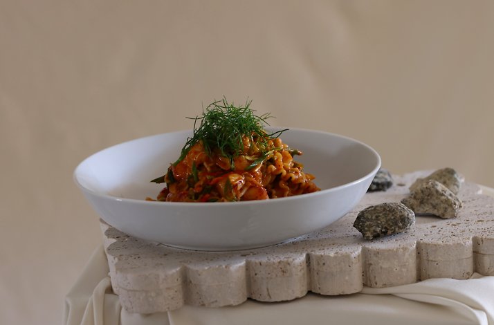 Contemporary Italian pasta dish mounded with herb-garnished tomato ragù, plated on a sculpted stone surface at Cento Pasta Bar.