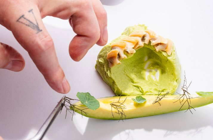 A hand embellish an avocado with leafs