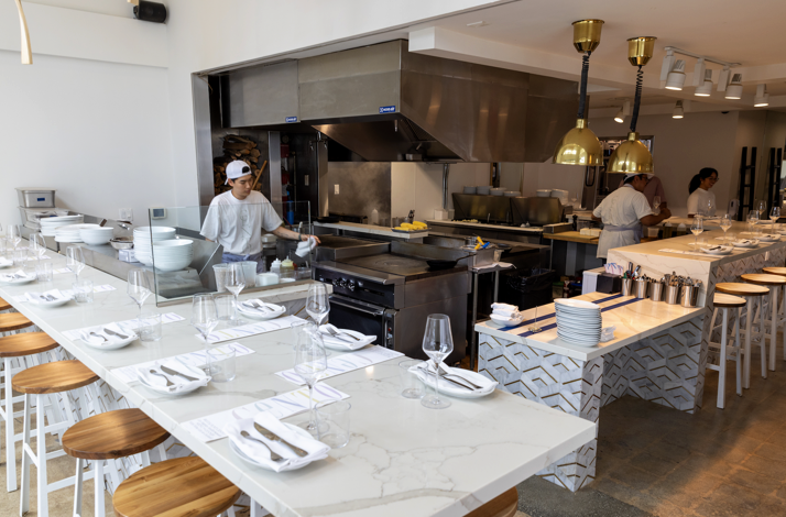 Modern open-kitchen dining room at CENTO Pasta Bar with chefs preparing food.