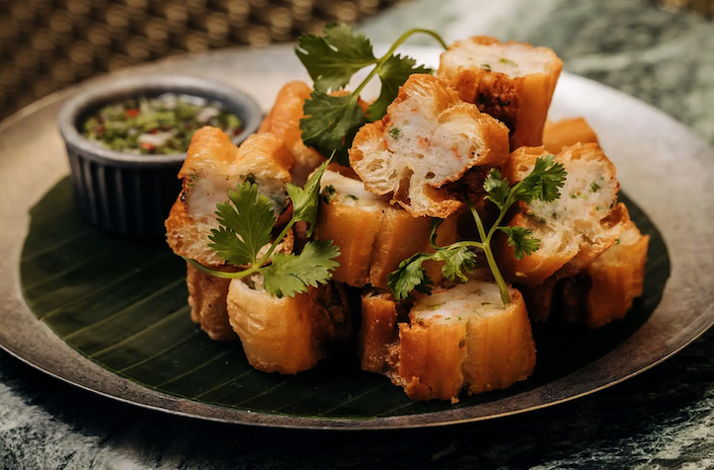 Golden fried bread cubes stacked on a banana leaf, garnished with cilantro and served with dipping sauce at Crying Tiger Chicago.