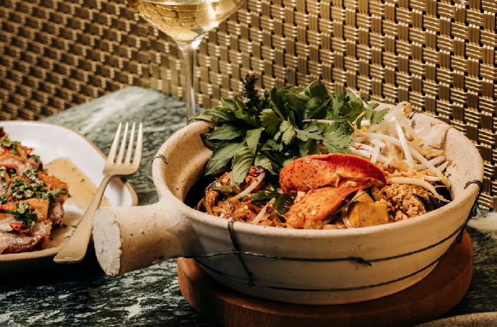 Stone bowl of lobster pad Thai garnished with cilantro and bean sprouts, part of Crying Tiger's Southeast Asian tasting menu.