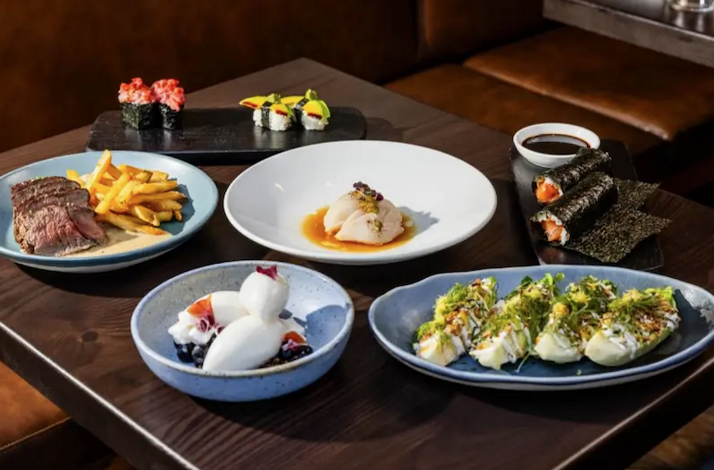 A Japanese-inspired tasting menu at Uchiko featuring a variety of dishes including steak frites, sushi, and scallop dishes.