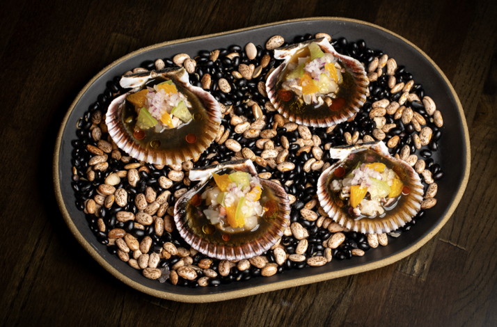 Four scallops served in shells atop mixed beans, topped with citrus, avocado, and red onion ceviche at Matilda, Chicago.