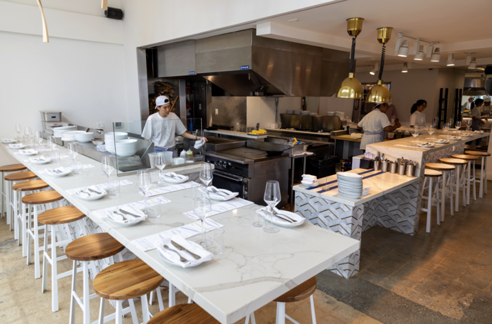 Modern open-kitchen dining room at CENTO Pasta Bar with chefs preparing food.