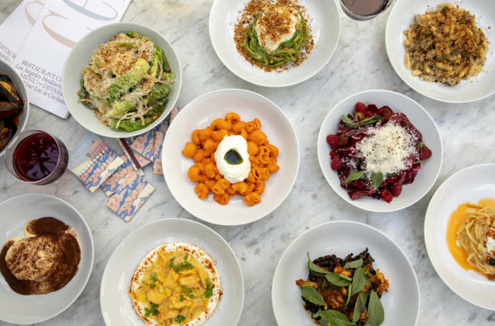 Bird's-eye view of Cento Pasta Bar's multicourse Italian menu, featuring varied pasta shapes, a salad, dessert, and wine pairings.