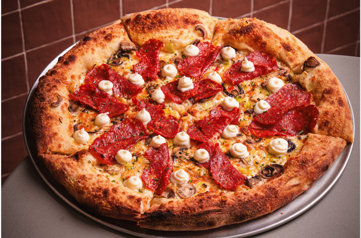 Gourmet pepperoni and mushroom pizza topped with cream swirls from Bar Bucce in Miami, Florida.